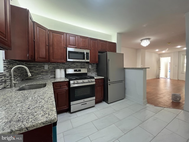 kitchen featuring stainless steel appliances, sink, tasteful backsplash, and light stone countertops