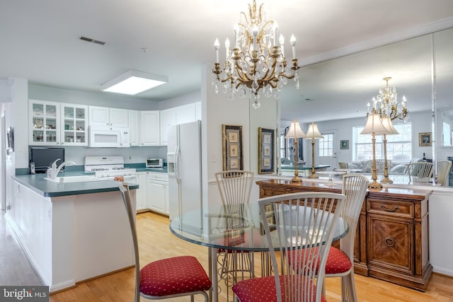 dining room with sink, an inviting chandelier, and light wood-type flooring