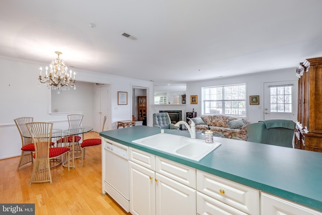 kitchen featuring white dishwasher, sink, an inviting chandelier, white cabinets, and light hardwood / wood-style floors