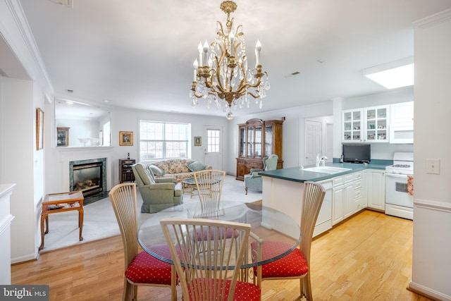 dining room featuring a notable chandelier, crown molding, light wood-type flooring, and sink