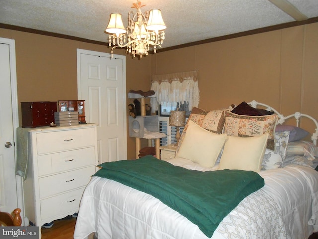 bedroom featuring crown molding, wood-type flooring, a textured ceiling, and a chandelier