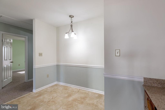 unfurnished dining area with a chandelier and light colored carpet