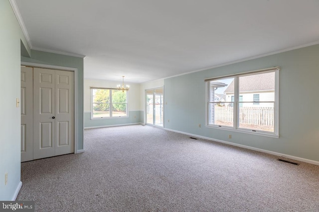 empty room featuring a notable chandelier, ornamental molding, and carpet floors