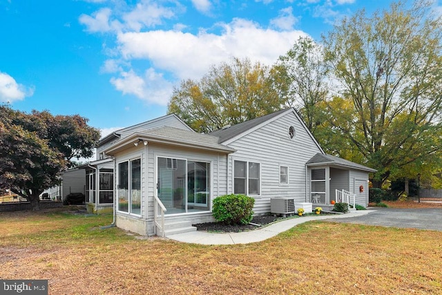 rear view of house featuring central AC, a sunroom, and a yard