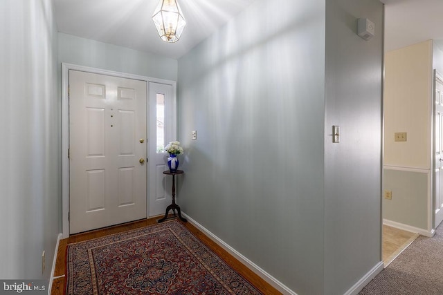 foyer entrance featuring a chandelier and carpet flooring