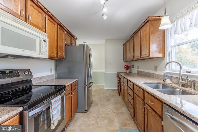 kitchen with stainless steel appliances, light tile patterned floors, sink, light stone countertops, and pendant lighting