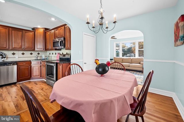 dining space with light hardwood / wood-style floors and a notable chandelier