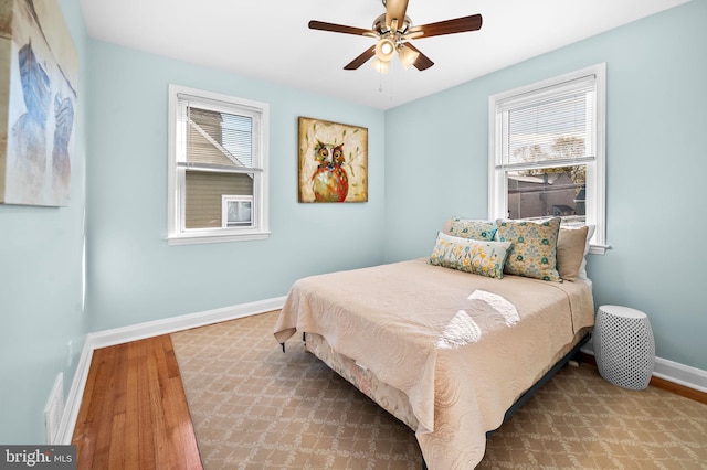 bedroom with hardwood / wood-style floors, multiple windows, and ceiling fan