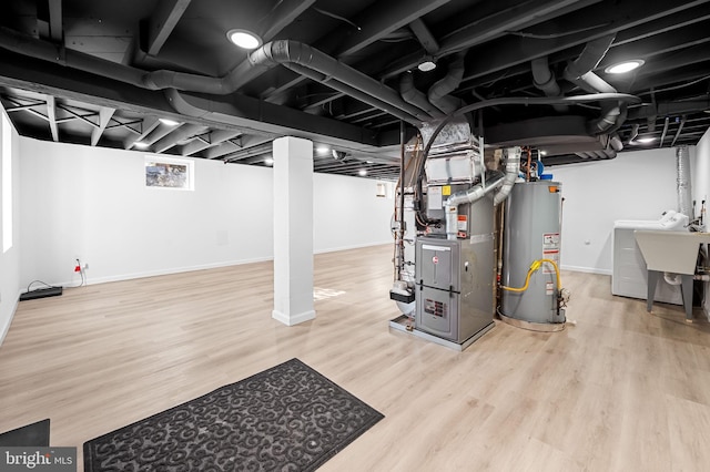 basement featuring water heater, washer / clothes dryer, heating unit, and wood-type flooring