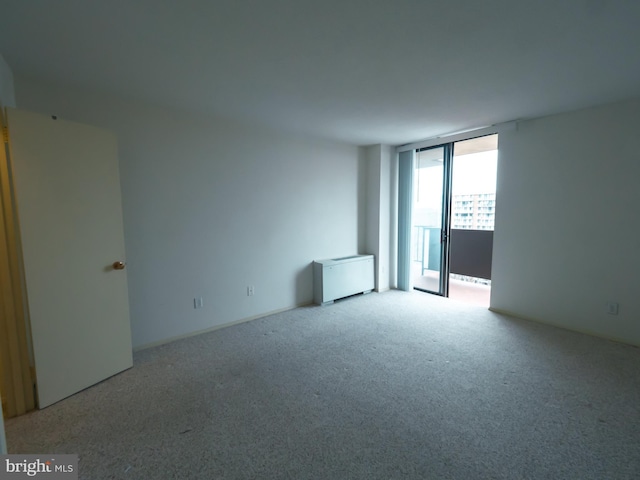 unfurnished room featuring a wall of windows and light colored carpet