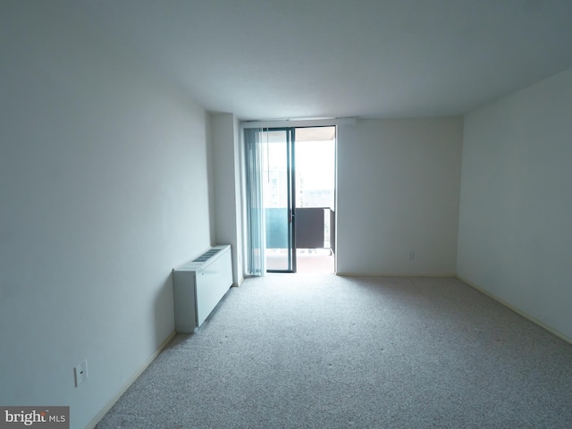 empty room featuring radiator heating unit and light carpet