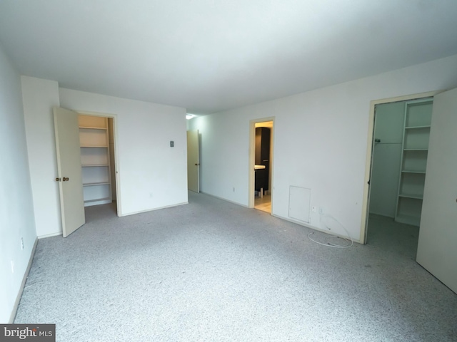 unfurnished bedroom featuring connected bathroom and a spacious closet