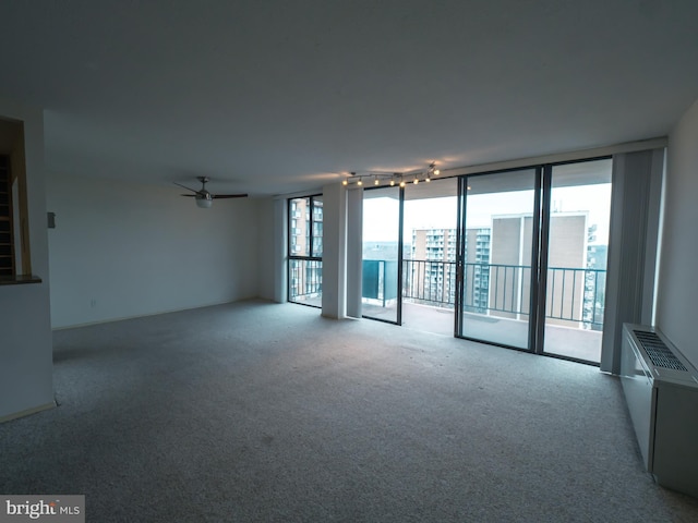 carpeted empty room featuring floor to ceiling windows and ceiling fan