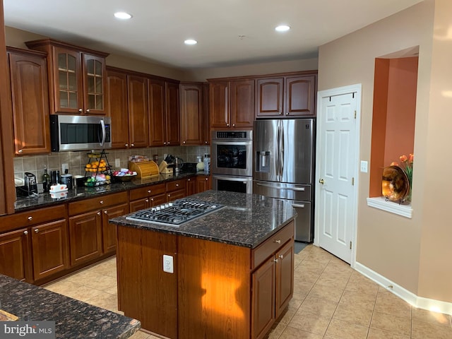 kitchen with a center island, stainless steel appliances, tasteful backsplash, and dark stone counters