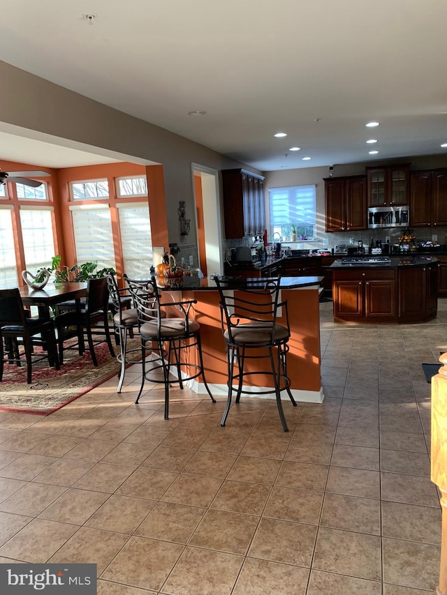 kitchen with a breakfast bar, tile patterned flooring, kitchen peninsula, and a healthy amount of sunlight