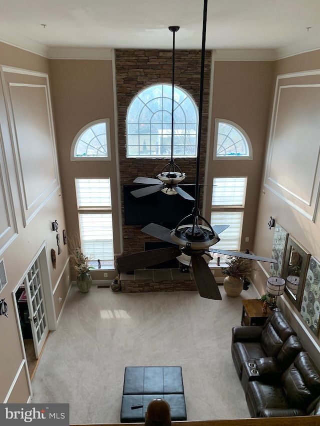 living room featuring carpet flooring, a towering ceiling, ceiling fan, and ornamental molding