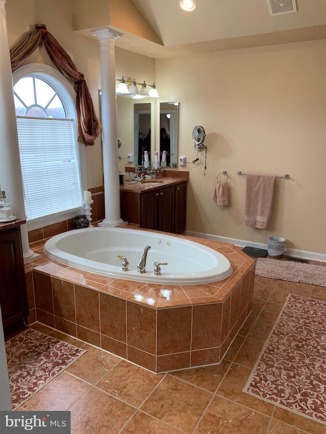 bathroom featuring tile patterned flooring, vanity, a relaxing tiled tub, and lofted ceiling