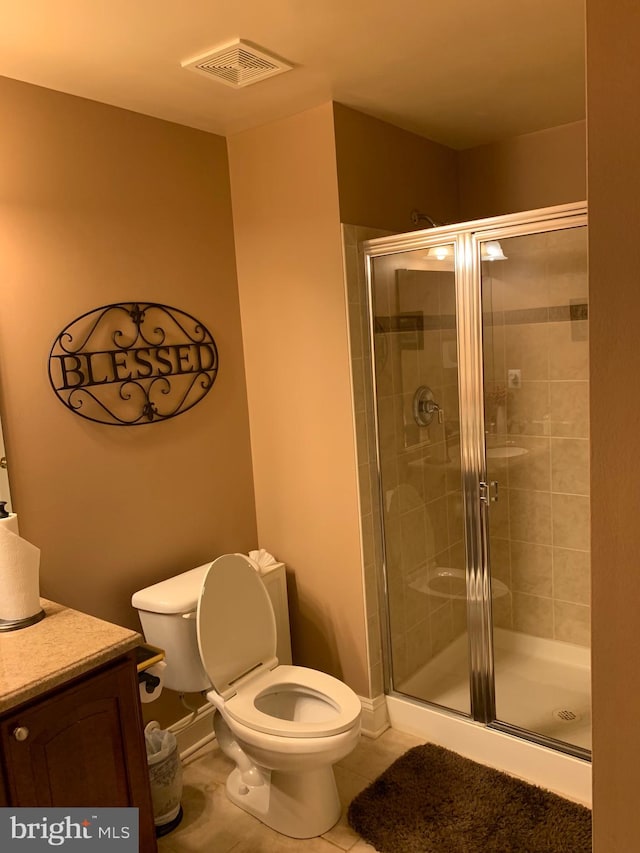 bathroom featuring tile patterned flooring, vanity, a shower with shower door, and toilet