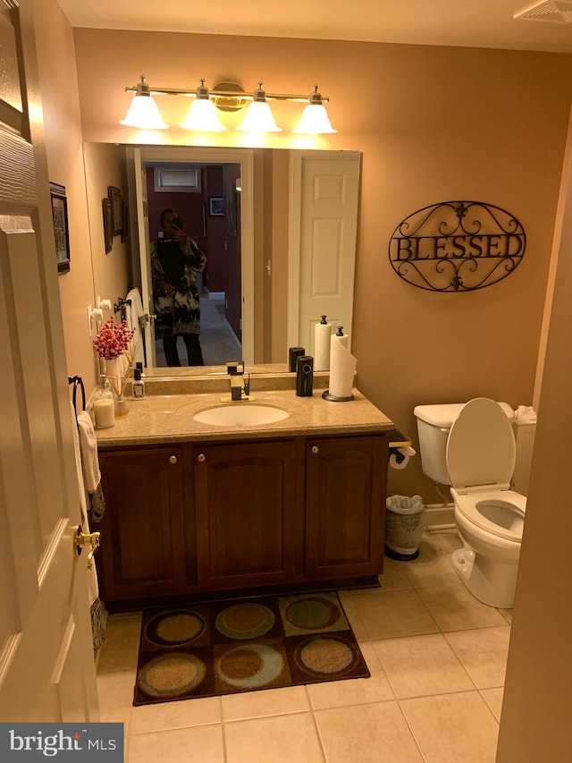 bathroom with toilet, vanity, and tile patterned floors