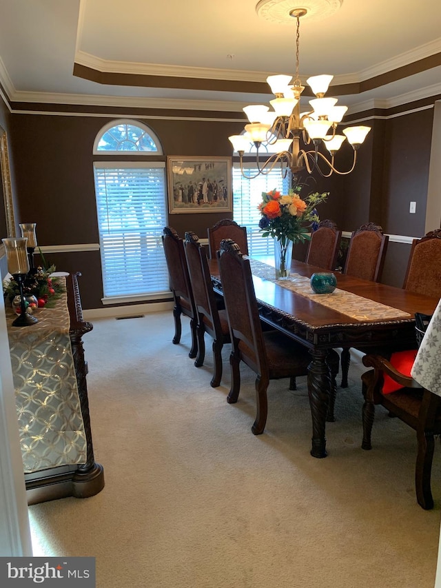 dining space featuring ornamental molding, carpet floors, a tray ceiling, and a notable chandelier