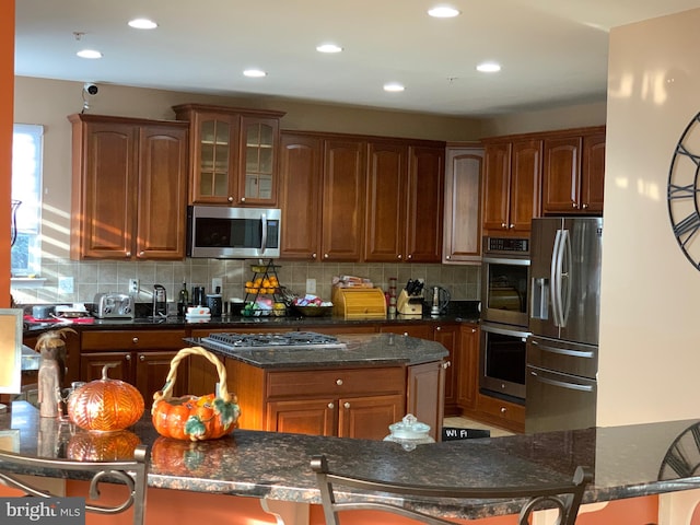 kitchen featuring backsplash, dark stone countertops, and appliances with stainless steel finishes