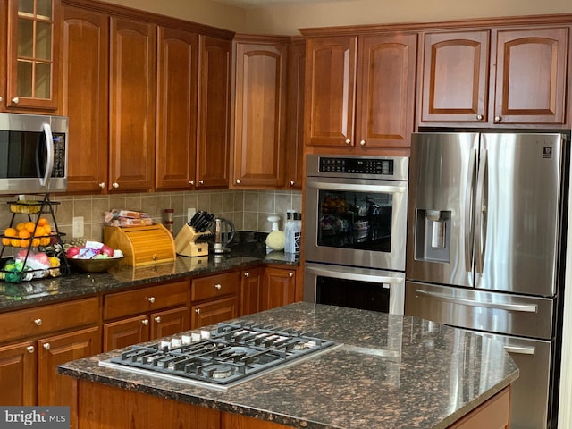 kitchen featuring backsplash, dark stone counters, and appliances with stainless steel finishes