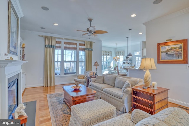 living area featuring recessed lighting, a fireplace with flush hearth, visible vents, baseboards, and crown molding