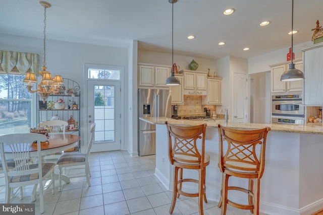 kitchen with appliances with stainless steel finishes, decorative light fixtures, and light stone countertops