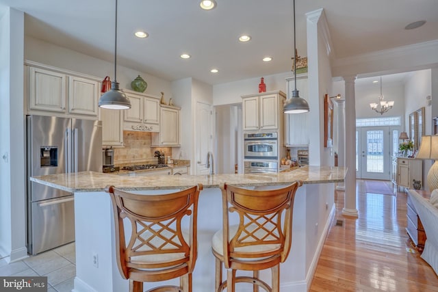 kitchen featuring a breakfast bar, cream cabinets, and pendant lighting