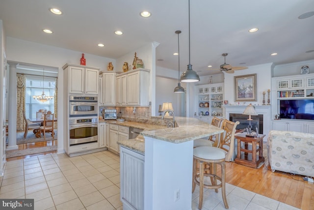 kitchen featuring decorative light fixtures, open floor plan, light stone countertops, a peninsula, and a kitchen bar