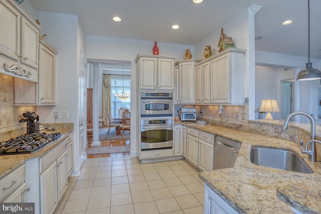 kitchen featuring stainless steel appliances, a sink, light stone countertops, tasteful backsplash, and pendant lighting