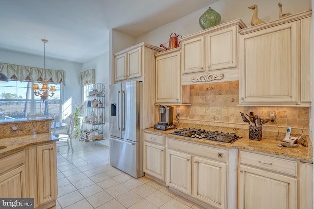 kitchen with light tile patterned floors, decorative backsplash, appliances with stainless steel finishes, light stone counters, and decorative light fixtures