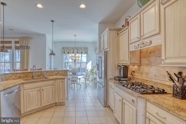 kitchen featuring light tile patterned floors, decorative backsplash, appliances with stainless steel finishes, hanging light fixtures, and a sink