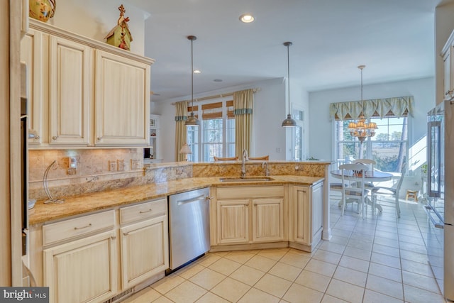 kitchen with a peninsula, appliances with stainless steel finishes, a sink, and decorative light fixtures