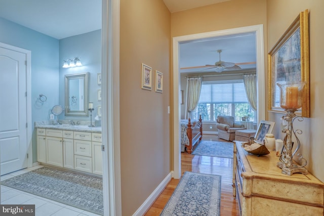 hall featuring light wood-style floors, a sink, and baseboards