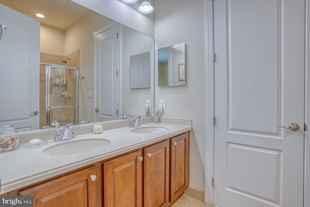 bathroom featuring double vanity, a stall shower, tile patterned flooring, and a sink