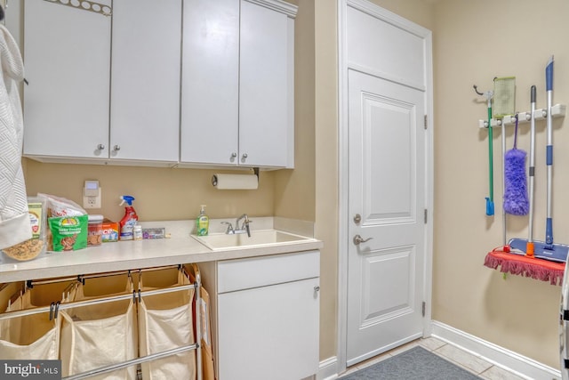 kitchen featuring light tile patterned floors, a sink, white cabinetry, baseboards, and light countertops