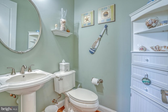 half bathroom with a sink, toilet, and baseboards