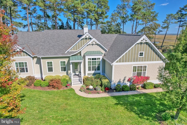 craftsman-style house with a shingled roof, a chimney, a front lawn, and board and batten siding