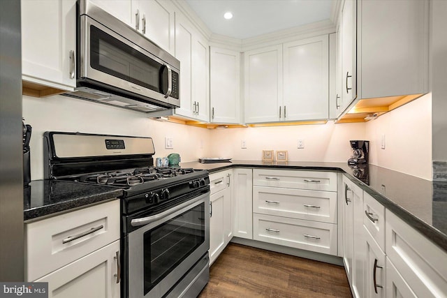 kitchen with dark stone counters, dark hardwood / wood-style flooring, white cabinetry, and appliances with stainless steel finishes