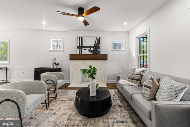 living room with ceiling fan, wood-type flooring, plenty of natural light, and a tile fireplace