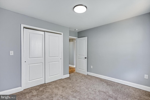 unfurnished bedroom with light colored carpet and a closet