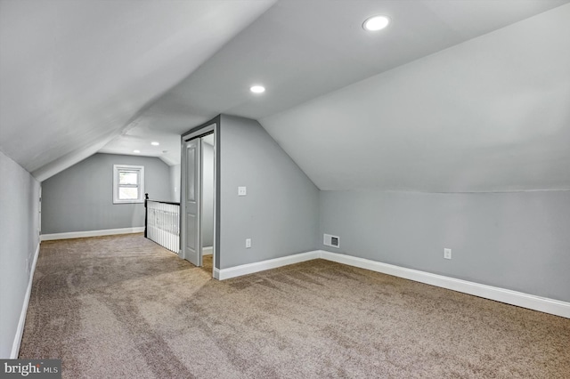 additional living space featuring vaulted ceiling and carpet floors