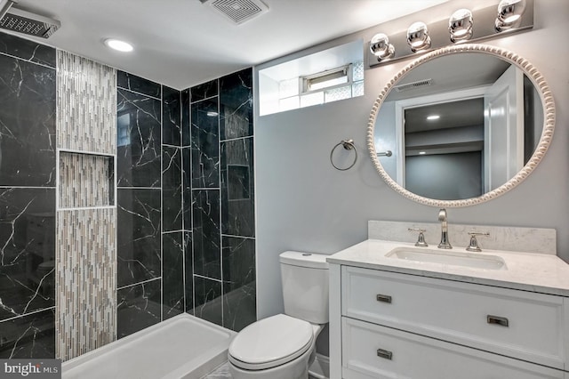 bathroom featuring a tile shower, vanity, and toilet