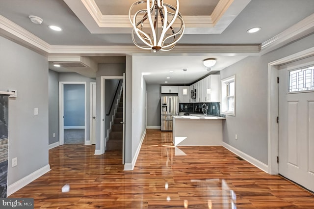 foyer entrance featuring wood-type flooring, a healthy amount of sunlight, crown molding, and a tray ceiling