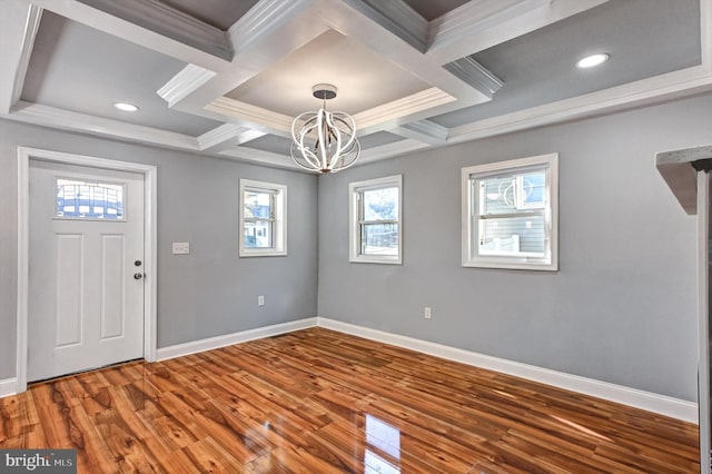 foyer entrance with wood-type flooring, a notable chandelier, coffered ceiling, ornamental molding, and beamed ceiling