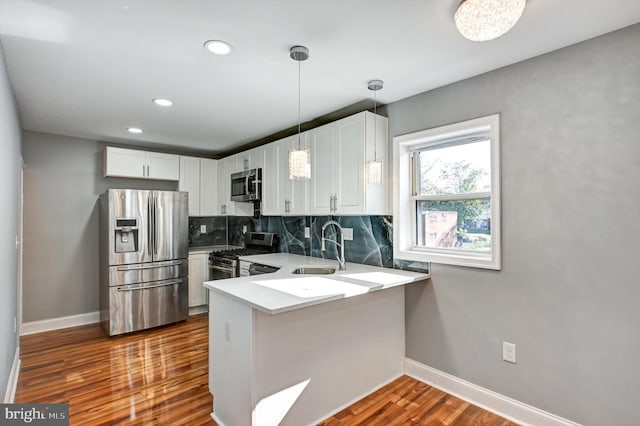 kitchen featuring white cabinetry, kitchen peninsula, appliances with stainless steel finishes, and dark hardwood / wood-style floors