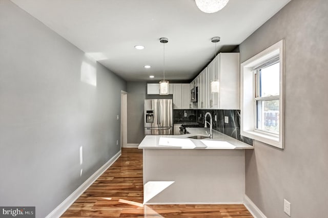 kitchen featuring tasteful backsplash, appliances with stainless steel finishes, dark hardwood / wood-style flooring, white cabinets, and kitchen peninsula