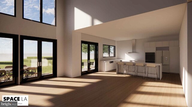 living room featuring french doors, light wood-type flooring, a high ceiling, and a wealth of natural light