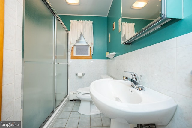 bathroom featuring toilet, tile patterned flooring, tile walls, and a shower with door